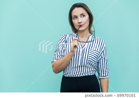 Hmm. Let my think. Blonde business woman boss wondering and imagination, and holding glasses. Studio shot on blue background 89970101