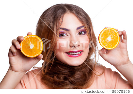 Young beautiful funny girl with orange slice and makeup and hairstyle looking at camera. studio shot, isolated on white background. . Young beautiful funny girl with orange slice and makeup and hairstyle looking at camera. studio shot, isolated on white background. . 89970166