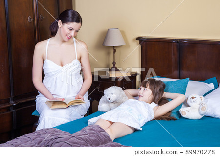 Mother teaches her daughter to read. Relationships between parents and children, education, comfortable life. Studio shot Mother teaches her daughter to read. Relationships between parents and children, education, comfortable life. Studio shot 89970278