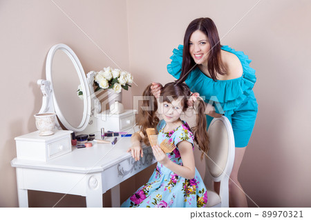 Mother hairdressing her preteen beautiful daughter at home. Mother hairdressing her preteen beautiful daughter at home. 89970321