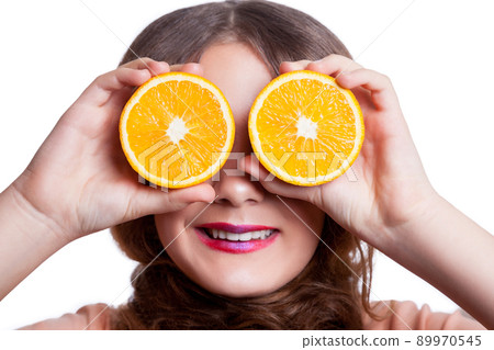 Young beautiful funny girl with orange slice and makeup and hairstyle looking at camera. studio shot, isolated on white background. . 89970545