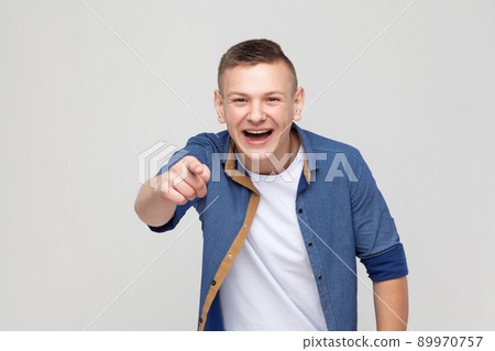 Happiness young boy pointing finger at camera and toothy smile. Studio shot Happiness young boy pointing finger at camera and toothy smile. Studio shot 89970757
