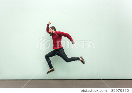Was late for work in firs day. Young adult bearded man running to the work. Outdoor, gray wall 89970830