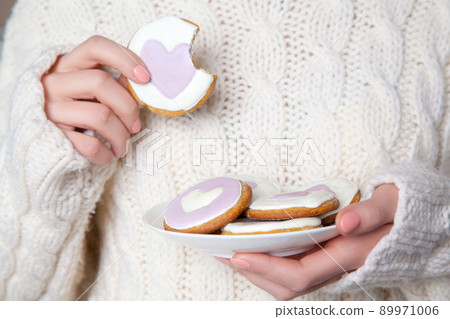 Closeup of woman with white sweater holding biscuit. indoor studio shot Closeup of woman with white sweater holding biscuit. indoor studio shot 89971006