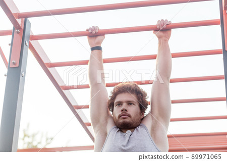 Close up. Horizontal bars. Young adult bearded redhead man, climb on bar. Outdoor Close up. Horizontal bars. Young adult bearded redhead man, climb on bar. Outdoor 89971065