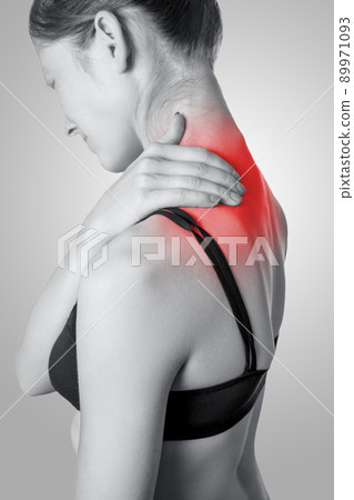 Closeup view of a young woman with shoulder or neck pain on gray background. Black and white photo with red dot 89971093