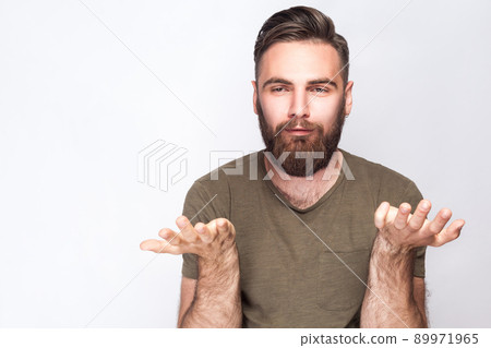 I don't know! Portrait of confused bearded man with dark green t shirt against light gray background. studio shot. . I don't know! Portrait of confused bearded man with dark green t shirt against light gray background. studio shot. . 89971965