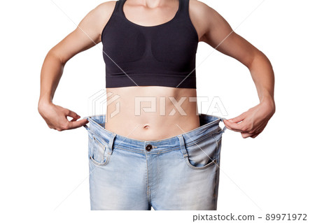 Close-up of slim waist of young woman in big jeans showing successful weight loss, isolated on white background, diet concept. 89971972