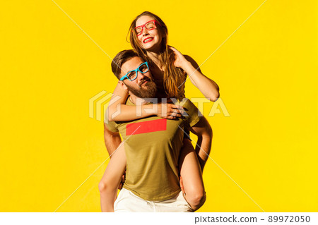 Piggyback. Happiness friend looking at camera and posing on yellow background. Studio shot Piggyback. Happiness friend looking at camera and posing on yellow background. Studio shot 89972050