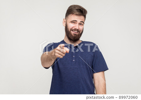 Jibe, bad taunt concept. Young adult man pointing finger and toothy smile. Studio shot, gray background 89972060