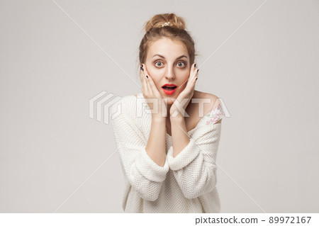 Shouting blonde open mouth, touching her cheeks. Studio shot, gray background Shouting blonde open mouth, touching her cheeks. Studio shot, gray background 89972167