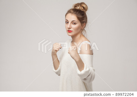 Fight and dangerous concept. Aggressive blonde woman standing in boxer pose. Studio shot, isolated on gray background Fight and dangerous concept. Aggressive blonde woman standing in boxer pose. Studio shot, isolated on gray background 89972204