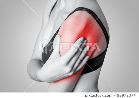 young woman with pain on her arm and shoulder on gray background. Black and white photo with red dot. 89972374