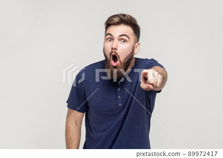 No way man! Look this! Surprised young adult man pointing finger at camera with open mouth and big eyes 89972417