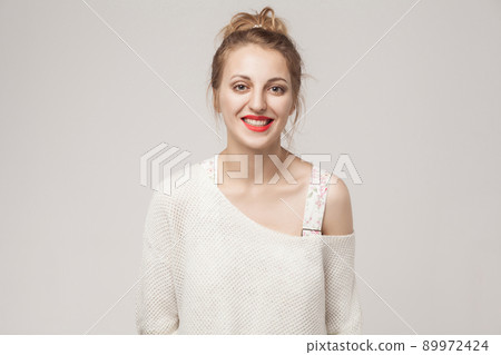 Laughing young blonde woman looking at camera and toothy smile. Studio shot, isolated on gray background 89972424