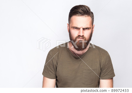 Portrait of angry sad bearded man with dark green t shirt against light gray background. studio shot. . 89972433