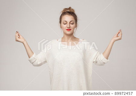 Blone young adult woman closed up, relax and doing youga asana. Studio shot, gray background Blone young adult woman closed up, relax and doing youga asana. Studio shot, gray background 89972457