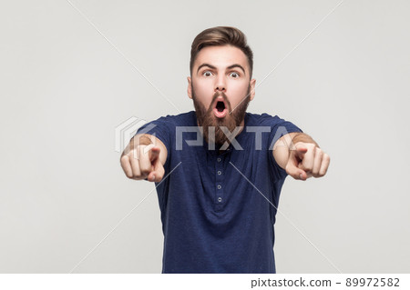 Hey you! Amazement bearded man pointing fingers at camera with open mouth and big eyes. Studio shot Hey you! Amazement bearded man pointing fingers at camera with open mouth and big eyes. Studio shot 89972582
