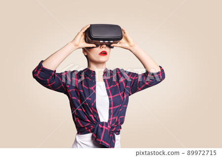 Young beautiful woman in casual style with virtual reality headset on beige background. studio shot. . 89972715