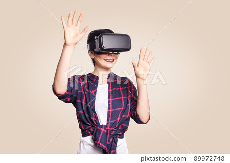 Young beautiful woman in casual style with virtual reality headset on beige background. studio shot. . 89972748