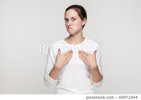 Bully girl showing hands himself and looking at camera. Indoor shot, gray background 89972844