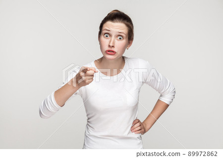 Warning sign. Serious man pointing finger at camera. Indoor shot, gray background 89972862