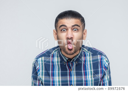 comic faces concept. Funny hipster showing stupid face and looking at camera. Studio shot 89972876