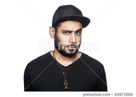 Portrait of young doubtful thinking man with black t-shirt and cap looking at camera with unsure eyes. studio shot, isolated on white background. 89973066