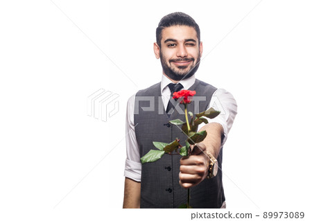 Handsome romantic happy man with rose flower. studio shot. isolated on white background. holding and giving flower and looking at camera and smiling with wink.. 89973089