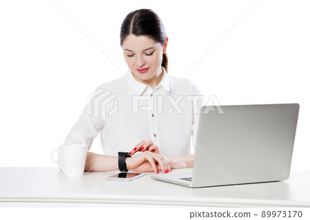 Portrait of happy attractive brunette businesswoman in white shirt sitting looking and touching her smartwatch display, reading something and smiling. indoor studio shot, isolated in white background. Portrait of happy attractive brunette businesswoman in white shirt sitting looking and touching her smartwatch display, reading something and smiling. indoor studio shot, isolated in white background. 89973170