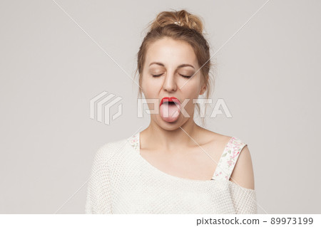 Funny woman closed eyes and tongue out . Studio shot, isolated on gray background 89973199