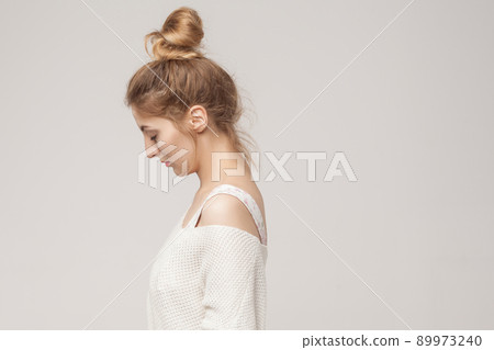 Side view young adult unwell blonde woman looking down. Studio shot Side view young adult unwell blonde woman looking down. Studio shot 89973240