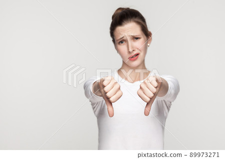 Unhappy woman demonstrate dislike sign. Studio shot, gray background 89973271