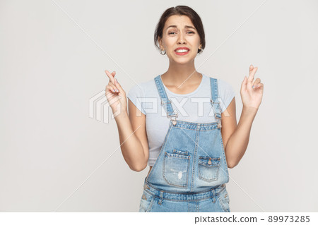 The very cunning woman, crossing fingers for good luck, hoping wishes will come true, looking up slyly. Indoor, studio shot 89973285