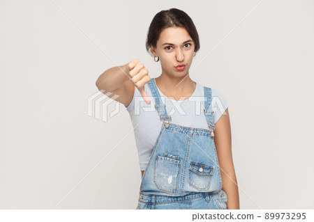 Young adult woman showing thumb down isolated on a gray background. Studio shot. Young adult woman showing thumb down isolated on a gray background. Studio shot. 89973295