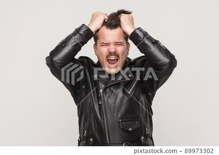 Anger man scream at camera and holding head. Studio shot Anger man scream at camera and holding head. Studio shot 89973302