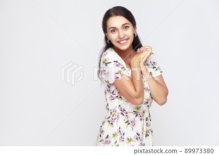 Cute and happiness woman in flowers dress, looking at camera and toothy smile. Studio shot, gray background Cute and happiness woman in flowers dress, looking at camera and toothy smile. Studio shot, gray background 89973380