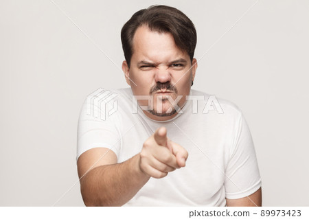 Anger adult man pointing finger at camera. Studio shot, isolated on gray background 89973423