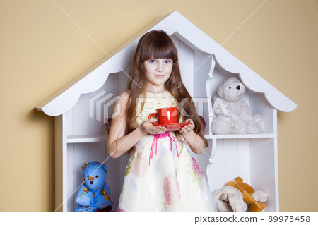 Happy little girl with cup of tea in her room. drinking and happy. studio shot. Happy little girl with cup of tea in her room. drinking and happy. studio shot. 89973458