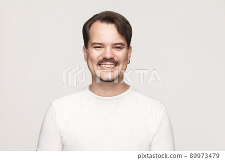 Happiness adult man, looking at camera and toothy smile. Indoor shot in gray background Happiness adult man, looking at camera and toothy smile. Indoor shot in gray background 89973479