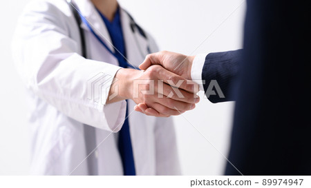 A businessman shaking hands with a healthcare professional 89974947