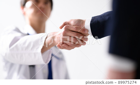A businessman shaking hands with a healthcare professional A businessman shaking hands with a healthcare professional 89975274