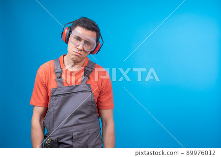Upset male carpenter in goggles and earmuffs Upset male carpenter in goggles and earmuffs 89976012