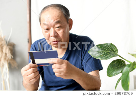 一位老人驚訝地看著銀行賬戶存摺 一位老人驚訝地看著銀行賬戶存摺 89978769