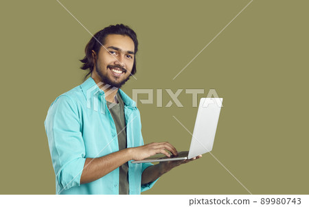 Happy young Indian student or IT specialist using his laptop computer and smiling Happy young Indian student or IT specialist using his laptop computer and smiling 89980743