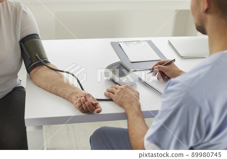 Senior woman with hypertension gets her blood pressure measured during checkup at hospital 89980745