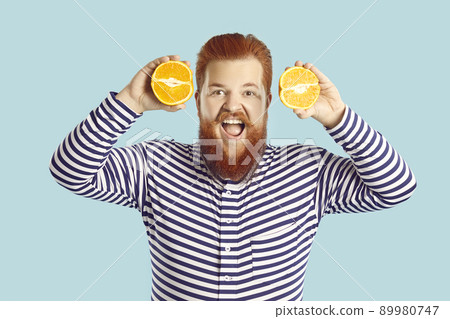 Funny happy fat man who likes eating fresh fruit is holding two orange halves and smiling Funny happy fat man who likes eating fresh fruit is holding two orange halves and smiling 89980747