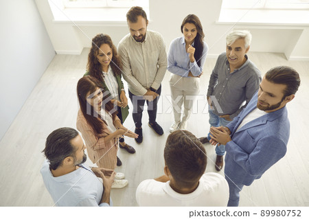 Group of people listening to business coach while standing in office during workshop 89980752