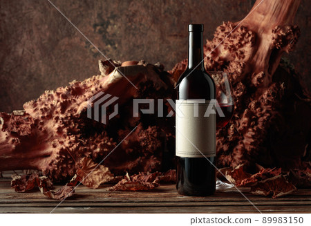 Bottle and glass of red wine on an old wooden table. 89983150
