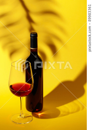Glass and bottle of red wine on a yellow background. Glass and bottle of red wine on a yellow background. 89983361